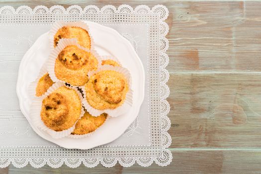 Close up of homemade coconut macaroons, cookie recipe in the oven on rustic wooden background. Top view with copy space.