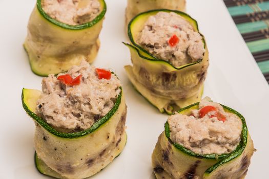 Grilled zucchini rolls with curd cheese and tuna on plate. Top view with copy space