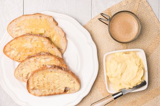 Fresh bread, homemade butter and coffee on wooden background. Top view with copy space.