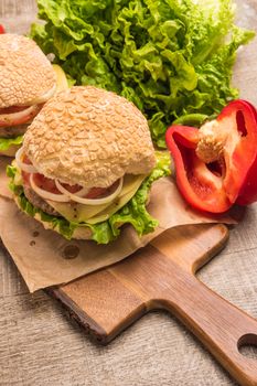 Two homemade vegetarian burgers with fresh organic vegetables on rustic wooden background. Top view with copy space.