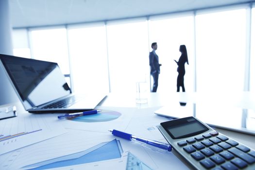 Financial reports, calculator and laptop on table in office