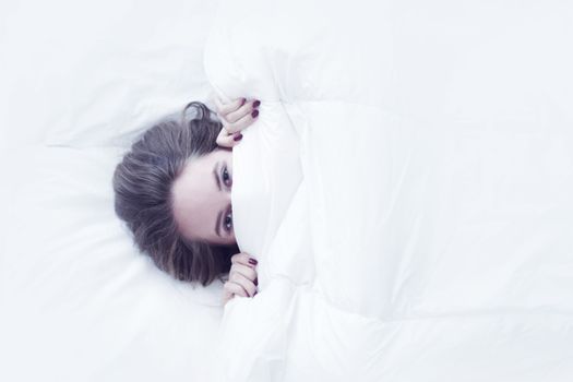 Young girl wake up in bed, top view