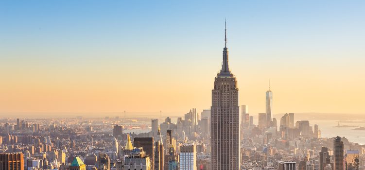 New York City. Manhattan downtown skyline with illuminated Empire State Building and skyscrapers at sunset seen from Top of the Rock observation deck. Vertical composition.