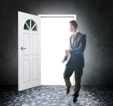 Image of young businessman standing with back opening door