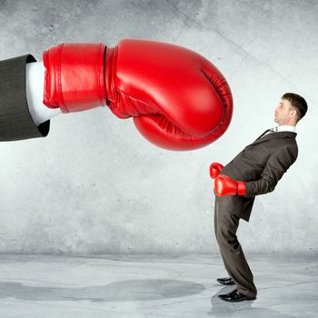 Businessman in boxing gloves against big boxing glove