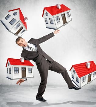 Businessman holding little houses on grey background