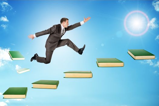 Businessman jumping over books in sky with sun