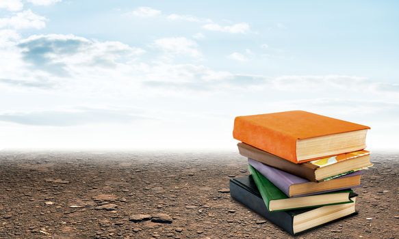 Stack of books on ground with sky view background