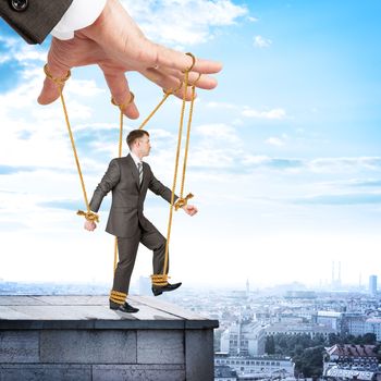 Image of businessman hanging on strings like marionette. Conceptual photography