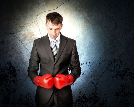 Businessman with boxing gloves on grey wall background with light