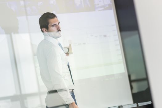 Businessman making a presentation in front of whiteboard. Business executive delivering a presentation to his colleagues during meeting or in-house business training. 