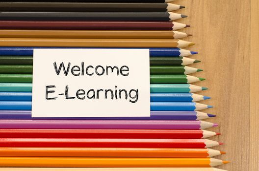 Welcome e-learning text concept and colored pencil on wooden background