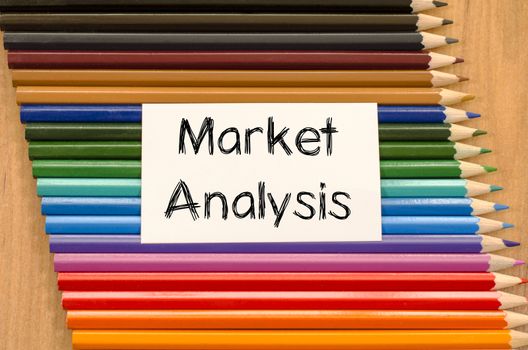 Market analysis text concept and colored pencil on wooden background