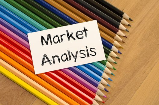 Market analysis text concept and colored pencil on wooden background