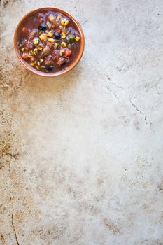 Bowl of fresh salsa on stone surface with copy space and viewed from above.