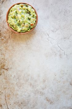 Bowl of fresh guacamole  n stone surface with copy space and viewed from above.
