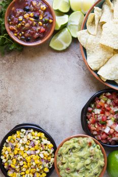 Tortilla chips served with guacamole, salsa, and pico de gallo with copy space, view from above.