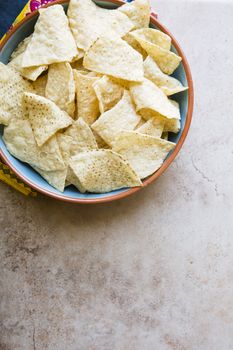 Bowl of fresh tortilla chips on stone surface with copy space.  View from above