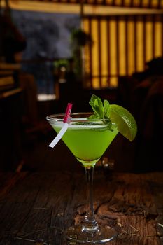 Martini glass with green cocktail with lime and mint leaves