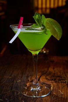 Martini glass with green cocktail with lime and mint leaves