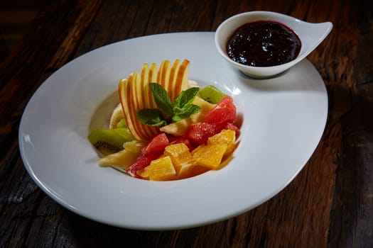 Healthy salad made of fresh fruitsin a white plate with sauce