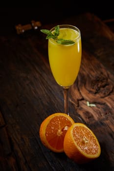 Orange cocktail decorated mint leaves and oranges on rustic wooden table