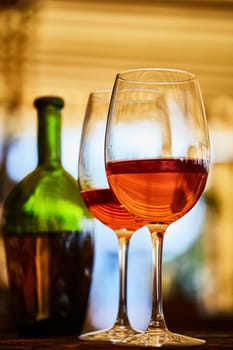 two wine glasses filled with red wine and wine bottle in background. Soft focus