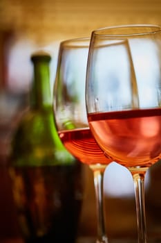 two wine glasses filled with red wine and wine bottle in background. Soft focus