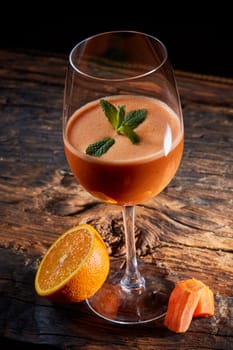 Orange carrot smoothie in glass decorated mint on wood