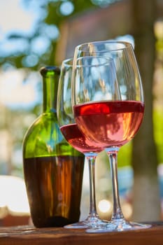 two wine glasses filled with red wine and wine bottle in background. Soft focus