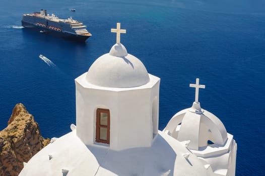 White orthodox church bell tower and sea with ships at background. Fira, Santorini Greece. Copyspace