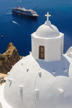 White orthodox church bell tower and sea with ships at background. Fira, Santorini Greece. Copyspace