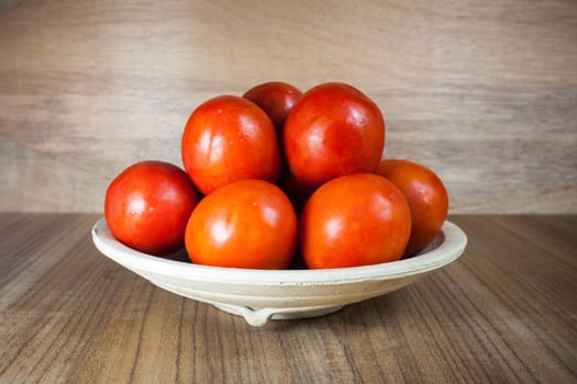 Close-up fresh ripe tomatoes on wood background .