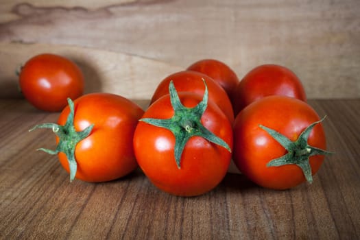 Close-up fresh ripe tomatoes on wood background .