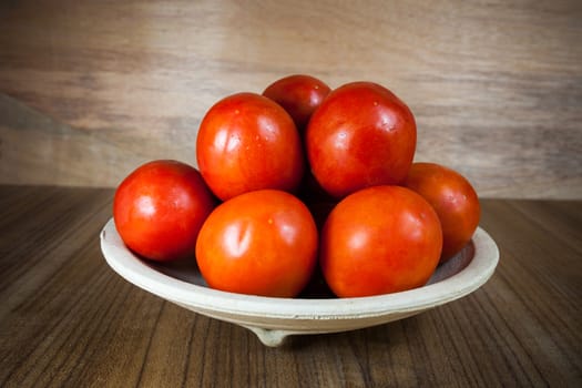 Close-up fresh ripe tomatoes on wood background .