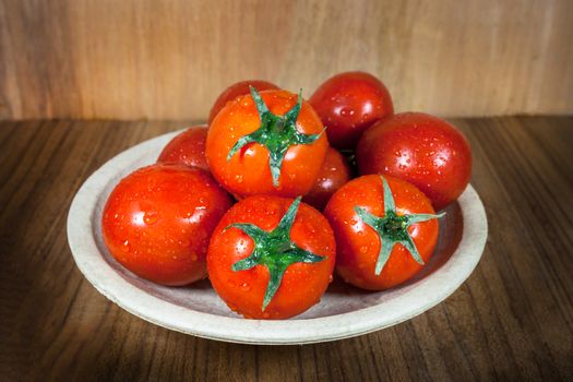 Close-up fresh ripe tomatoes on wood background .