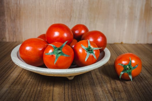 Close-up fresh ripe tomatoes on wood background .