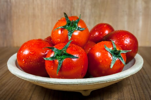 Close-up fresh ripe tomatoes on wood background .