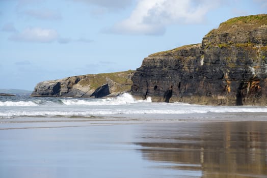 beautiful soft waves break on the beach cliffs at ballybunion