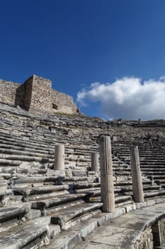 View of Miletus amphitheater in Aydin, Turkey with stone stairs on bright blue sky background.