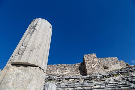 View of Miletus amphitheater in Aydin, Turkey with stone stairs on bright blue sky background.