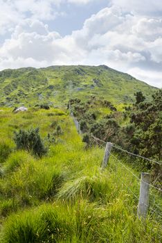 view from a beautiful hiking route the kerry way in ireland of fence leading to rocky mountains