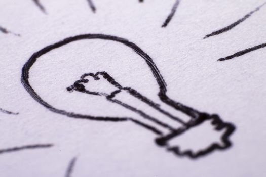 a pen drawing of a lightbulb on paper close up, a symbol of an idea or putting it to paper