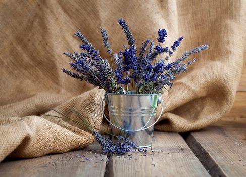 Lavender flowers in an iron bucket on a wooden background