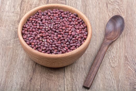 Bowl with beans and wooden spoon on a brown wooden background