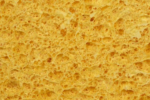 Textured surface of the porous yellow sponge close-up. For background.