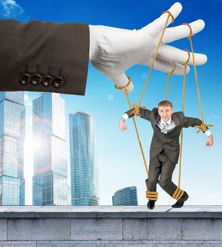 Image of businessman hanging on strings like marionette. Conceptual photography