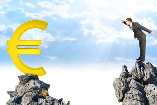 Businessman standing on edge of rock mountain and looking at euro sign