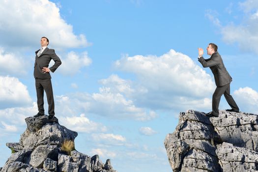 Businessman screaming to another businessman and standing on the mountain