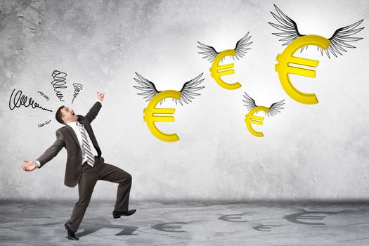 Surprised business man looking at flying euro signs on grey background